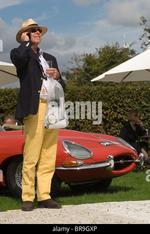 Pantalon jaune, blazer bleu et chapeau panama en paille. Retraite, un homme retraité un week-end au Goodwood Festival of Speed profitant de son temps libre, habillé intelligemment. Parler sur un téléphone portable. Goodwood Sussex Royaume-Uni. HOMER SYKES des années 2010 2010 Banque D'Images