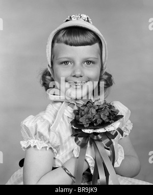 1950 CHILD HOLDING FLOWERS SMILING AT CAMERA Banque D'Images