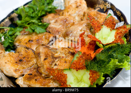 Couper un poulet rôti et décoré avec des fleurs de concombre, persil et aneth Banque D'Images