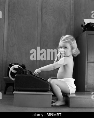 1940 enfant assis à taper sur l'ajout de l'EXPRESSION DU VISAGE DRÔLE DE MACHINE Banque D'Images