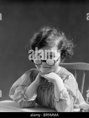 1930 PETITE FILLE PORTRAIT SMILING portant des lunettes rondes GRAND LOOKING AT CAMERA Banque D'Images