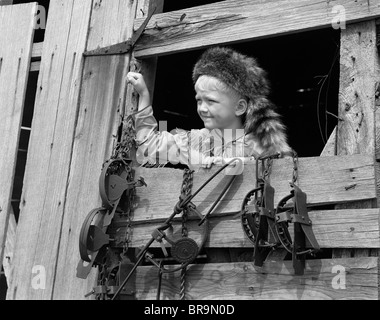 1950 garçon vêtu de COONSKIN HAT & Gilet à franges comme Davy Crockett à l'EXTÉRIEUR DANS LA FENÊTRE DE LA GRANGE Banque D'Images