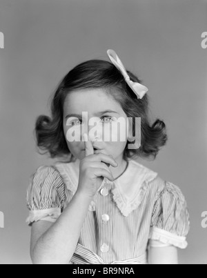 1940 Petite fille faire humble geste collés sur des lèvres LOOKING AT CAMERA Banque D'Images