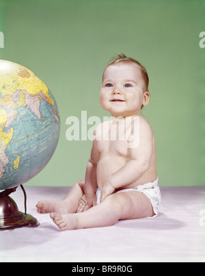 1960 SMILING BABY WEARING COUCHE ASSIS À CÔTÉ TERRE GLOBE Banque D'Images