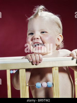 1960 RIRE BLOND BÉBÉ EN BERCEAU OU LE PARC Banque D'Images