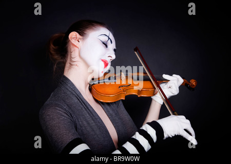 Femme mime dans gants blancs qui joue du violon sur un fond noir Banque D'Images