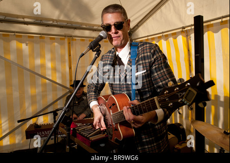 Un homme portant des lunettes de lecture d'une guitare acoustique semi dans un groupe, UK Banque D'Images