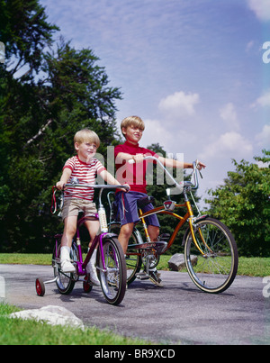 Années 1970 Années 1960 deux garçons faire du vélo en été, parc Banque D'Images