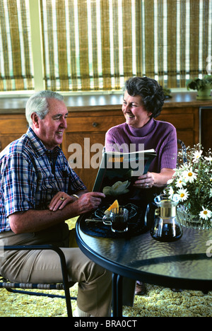 COUPLE ASSIS À TABLE AVEC LE CAFÉ READING MAGAZINE Banque D'Images
