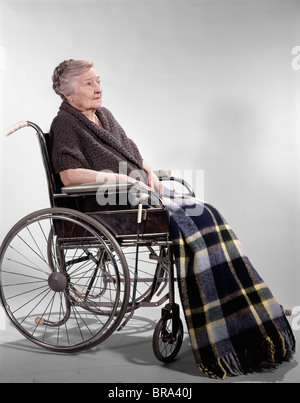 1960 1960 PERSONNES ÂGÉES SENIOR RETRO WOMAN SITTING IN WHEELCHAIR COUVERTURE PLAID CHÂLE SOLITAIRE TRISTE santé Vieillissement Banque D'Images