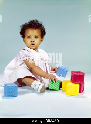 1960 Africains-Américains tout-petit bébé fille en robe rose PLAYING WITH TOY BLOCKS Banque D'Images