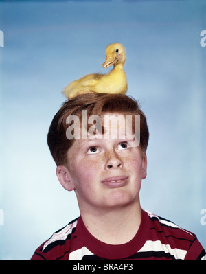 Années 1950 Années 1960 AVEC Bébé garçon petit canard assis sur sa tête l'EXPRESSION SUR LE VISAGE DRÔLE humoristique Banque D'Images