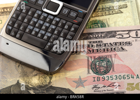 Mobile cell phone smartphone sur un tas de billets en dollars us Banque D'Images