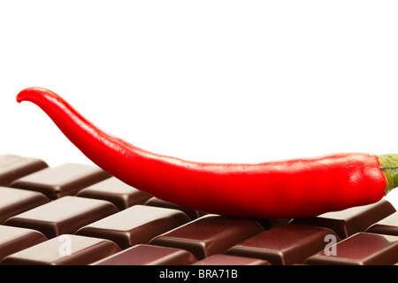 Red chili sur une barre de chocolat noir sur fond blanc Banque D'Images