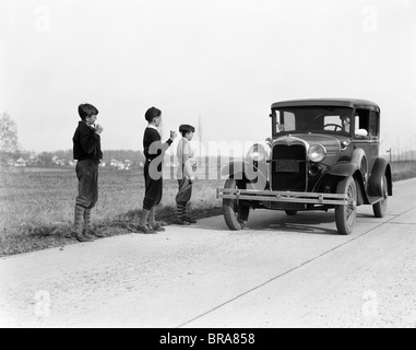 Années 1930 Années 1920 homme conduisant une voiture Ford modèle 3 garçons de l'autostop Banque D'Images