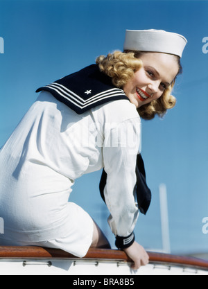 Années 1940 Années 1950 SMILING BLONDE FEMME en costume de marin à la Par-dessus son épaule Banque D'Images