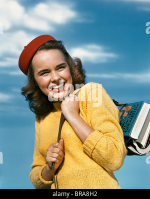 Années 1940 Années 1950 SMILING GIRL HOLDING Chandail rouge jaune TAM SCHOOL BOOKS OVER SHOULDER Banque D'Images