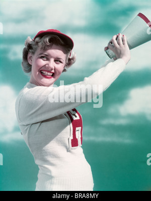 Années 1940 Années 1950 SMILING WOMAN WEARING CHEERLEADER LETTRE VARSITY SWEATER POINTING Banque D'Images