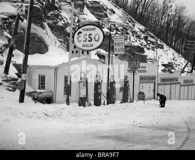 1940 SERVICE STATION DANS LES MONTAGNES EN HIVER, PLUSIEURS POMPES À ESSENCE GARAGES ET PÉTROLE ET GAZ SIGNE Banque D'Images