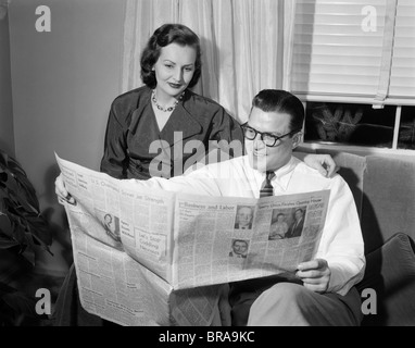 1950 HOMME FEMME COUPLE READING NEWSPAPER Banque D'Images