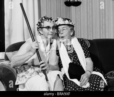 Années 1950 Années 1960 DEUX FEMMES ÂGÉES COMMÉRAGE DES CARACTÈRES D'UNE FEMME AVEC LES BIGOUDIS AUTRES avec chapeau Banque D'Images