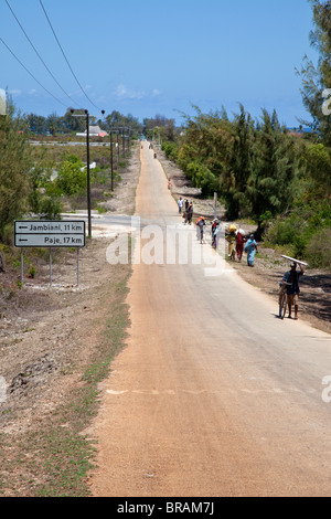 Makunduchi, Zanzibar, Tanzanie. Les cyclistes et les femmes transportant des charges marcher jusqu'à la colline à l'extérieur de la ville. Banque D'Images