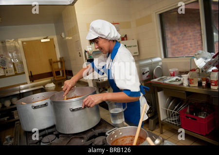 Cuisinier de l'école à préparer le dîner dans une cuisine de l'école primaire, UK Banque D'Images