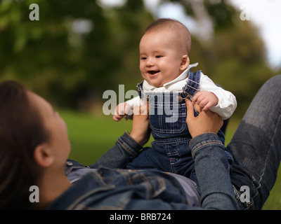 Mère jouant avec un sourire heureux bébé de quatre mois garçon dans la nature Banque D'Images