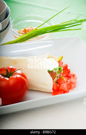 Falafel traditionnelle frais emballage sur le pain pita avec des tomates fraîches hachées Banque D'Images