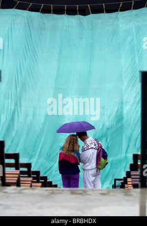 Deux spectateurs à l'abri sous le parapluie pluie s'arrête de jouer au tournoi de tennis Banque D'Images