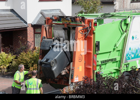 Ben les hommes de vider les ordures ménagères de wheelie bins en camion dans la rue. Anglesey au nord du Pays de Galles, Royaume-Uni, Angleterre. Banque D'Images