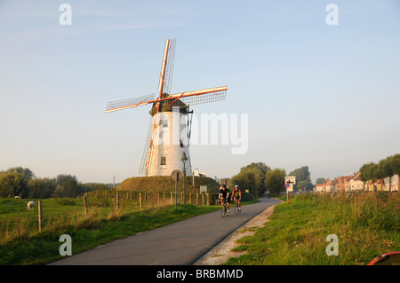 La Belgique. Les cyclistes PASSÉ MOULIN PRÈS DE LA VILLE MÉDIÉVALE DE BRUGES en Région flamande Banque D'Images