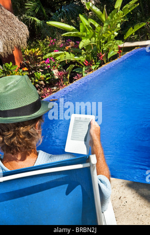 La lecture de l'homme e-book sur chaise extérieur Banque D'Images