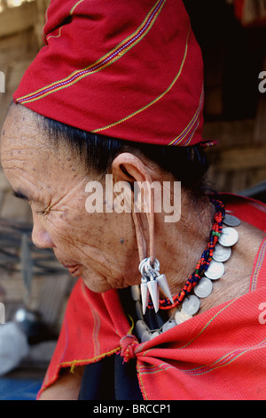 Un 'Karen' big ear femme de réfugiés de Birmanie prend un moment pour réfléchir sur le porche de sa maison à Ban Nai Soi, en Thaïlande. Banque D'Images