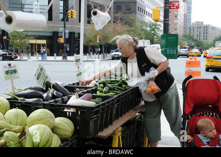 Une femme avec un bébé dans une poussette acheter des légumes au marché des agriculteurs dans la région de Battery Park City, un quartier de Manhattan. Banque D'Images