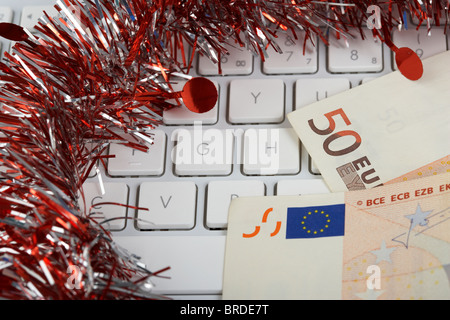 Pile de cinquante billets sur le clavier d'un ordinateur avec des guirlandes de Noël Décoration Banque D'Images