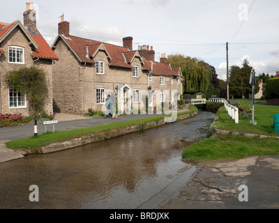 Un homme se promène avec son chien par les Ford à Hovingham North Yorkshire Banque D'Images