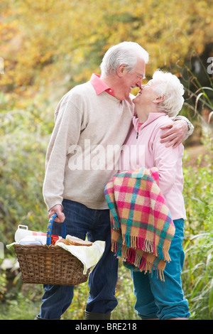 Romantic Senior Couple Outdoors avec panier pique-nique en forêt d'automne Banque D'Images