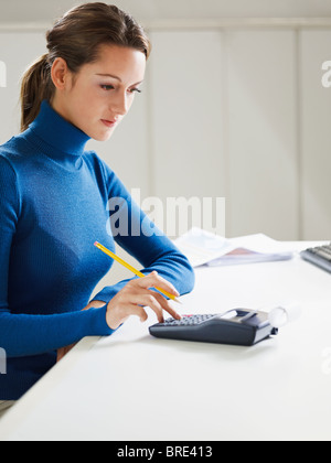 Woman using calculator in office Banque D'Images