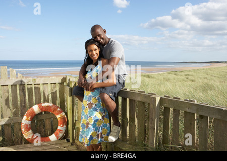 Couple debout par clôture en bois de cabane de plage entre les Dunes Banque D'Images