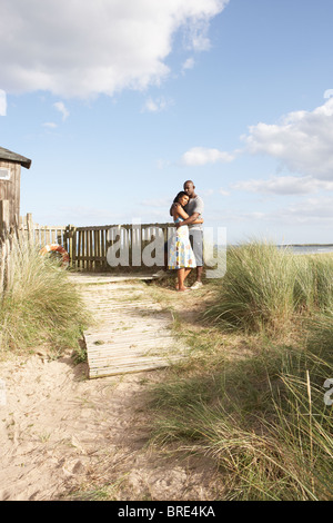 Couple debout par clôture en bois de cabane de plage entre les Dunes Banque D'Images