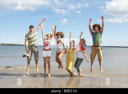 Groupe d'amis adolescents s'amusant sur plage ensemble Sauter dans l'air Banque D'Images