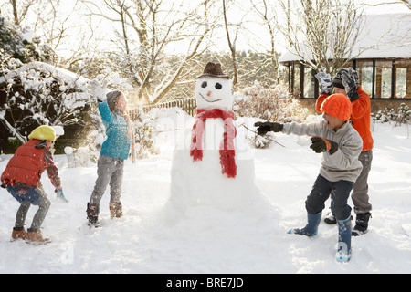 Mère et enfants en jardin Bâtiment Snowman Banque D'Images