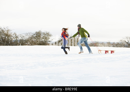 Woman Pulling Sled à travers champ neigeux Banque D'Images