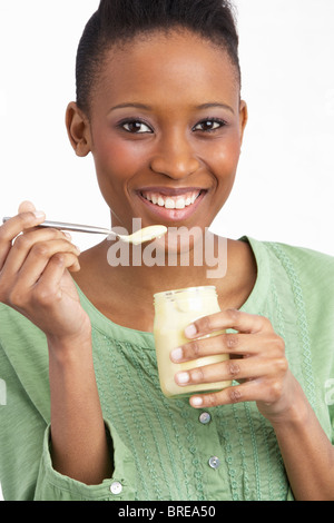 Young Woman Eating Yoghurt en Studio Banque D'Images