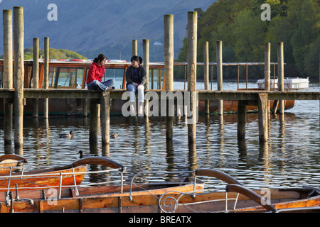 Deux filles bavardant assis sur le débarcadère de la barques sur Derwentwater, Keswick Banque D'Images