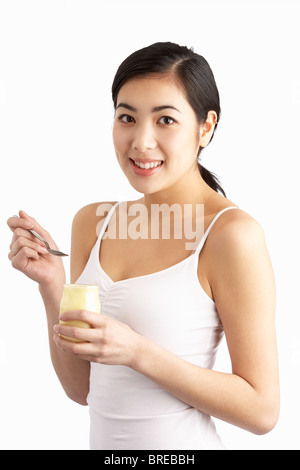 Young Woman Eating Yoghurt en Studio Banque D'Images