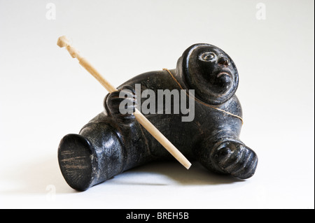 La sculpture inuit d'un homme avec un harpon, stéatite gris et l'os. Banque D'Images