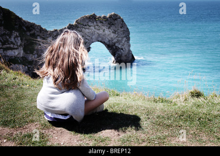 Jeune fille s'assit à Durdle Door, Dorset, Angleterre, Royaume-Uni