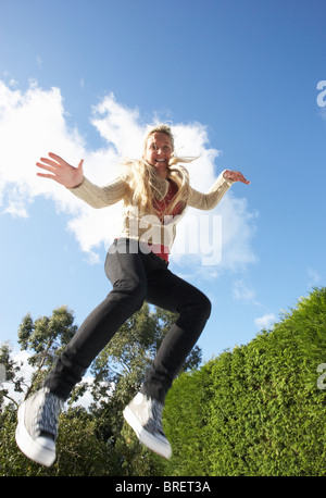 Young Woman Jumping on Trampoline pris dans les airs Banque D'Images